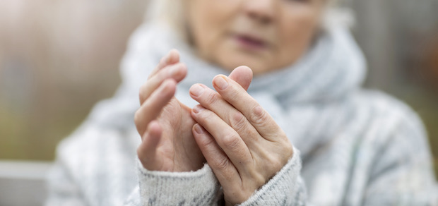 women looking at her hand while experiencing joint pain