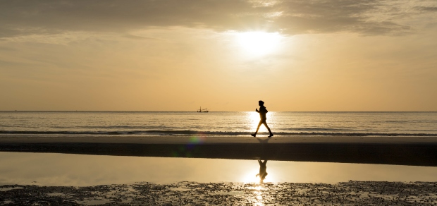 The silhouette of a person running on the beach at sunset. 