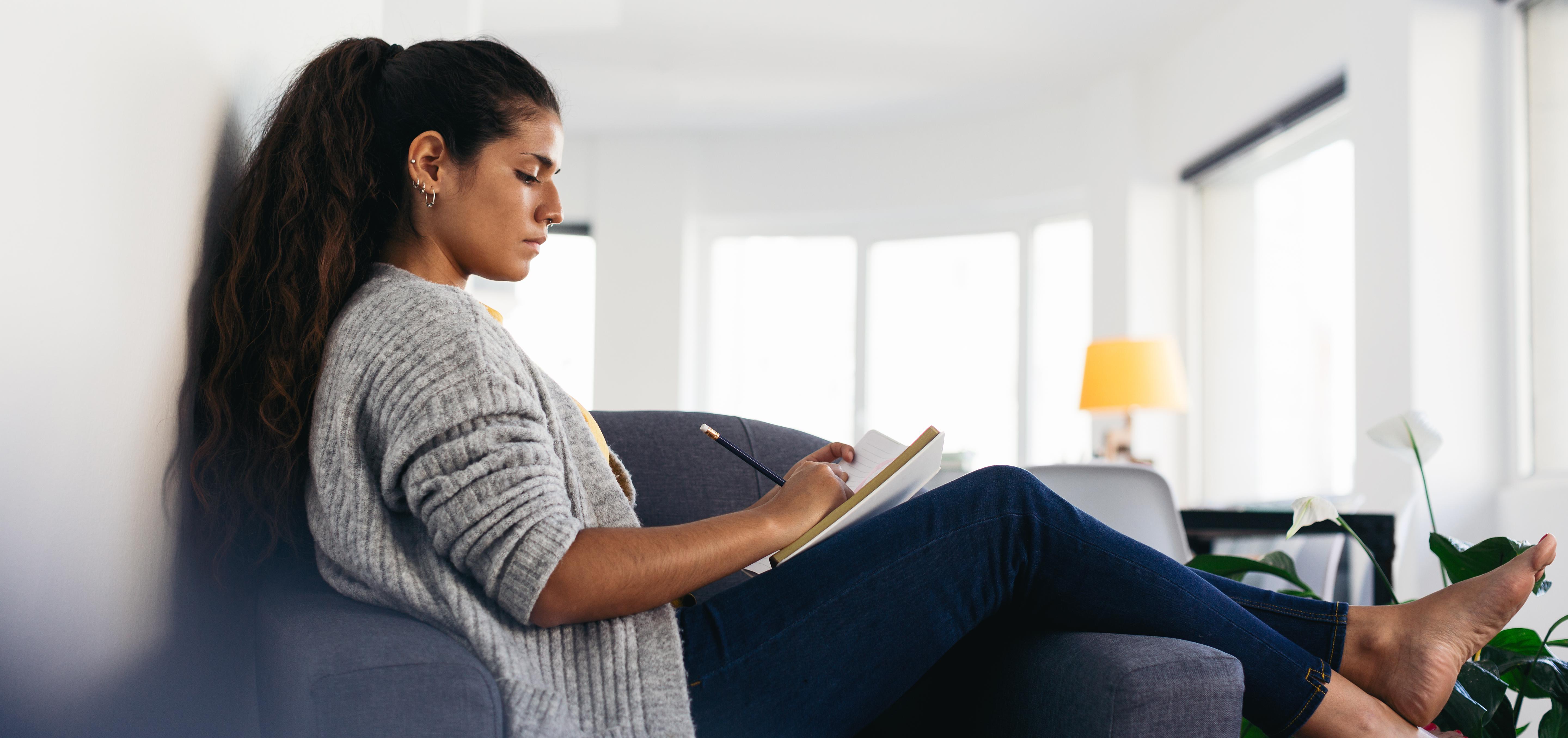 woman writing in a notebook with a pencil