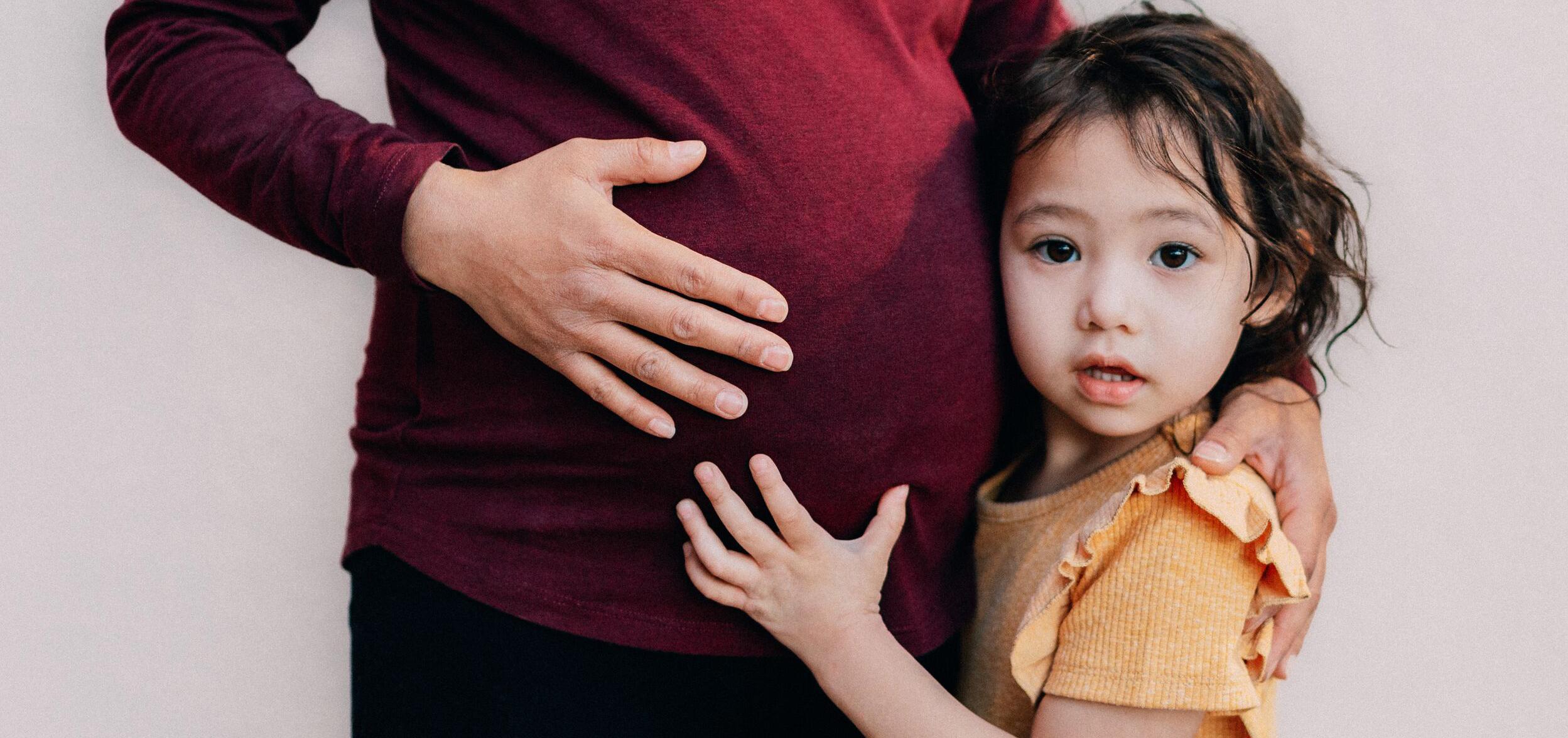 pregnant woman holding her daughter close