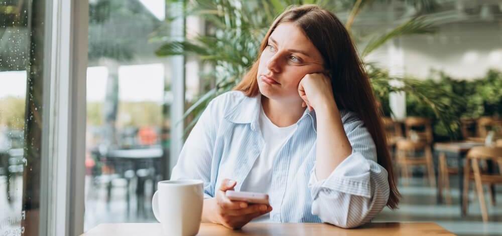 pensive woman looking out the window in a cafe