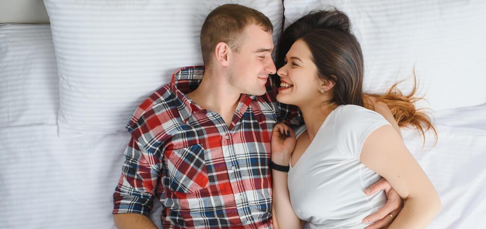 pregnant woman lying in bed with her partner