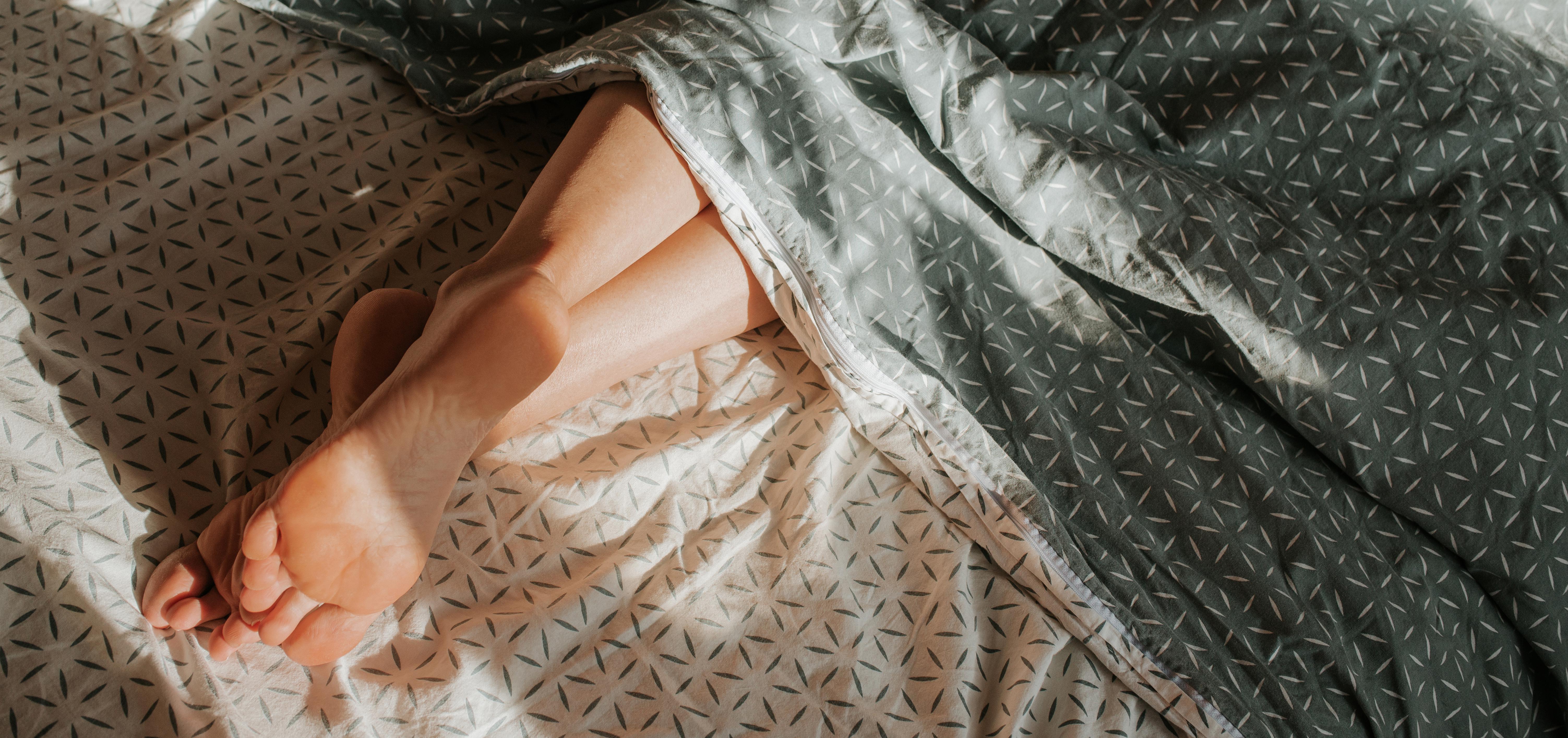 woman's feet peeking out from under patterned bed sheets