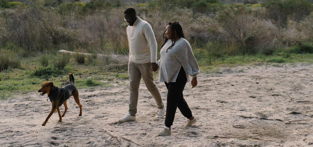 couple holding hands and walking their dog