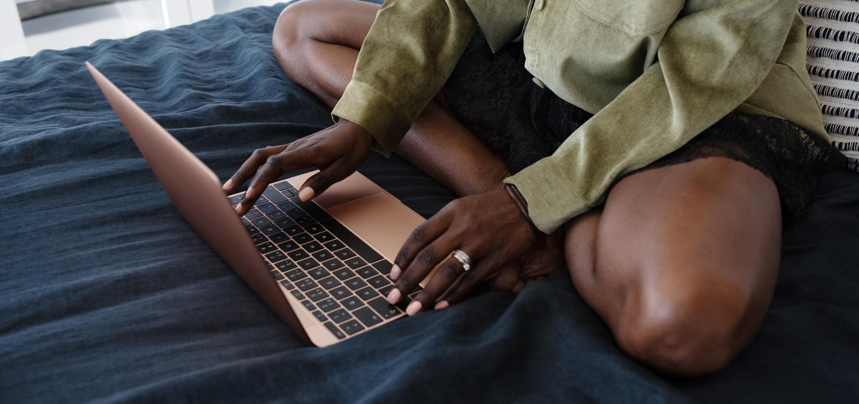 Woman at rose gold computer, typing. 