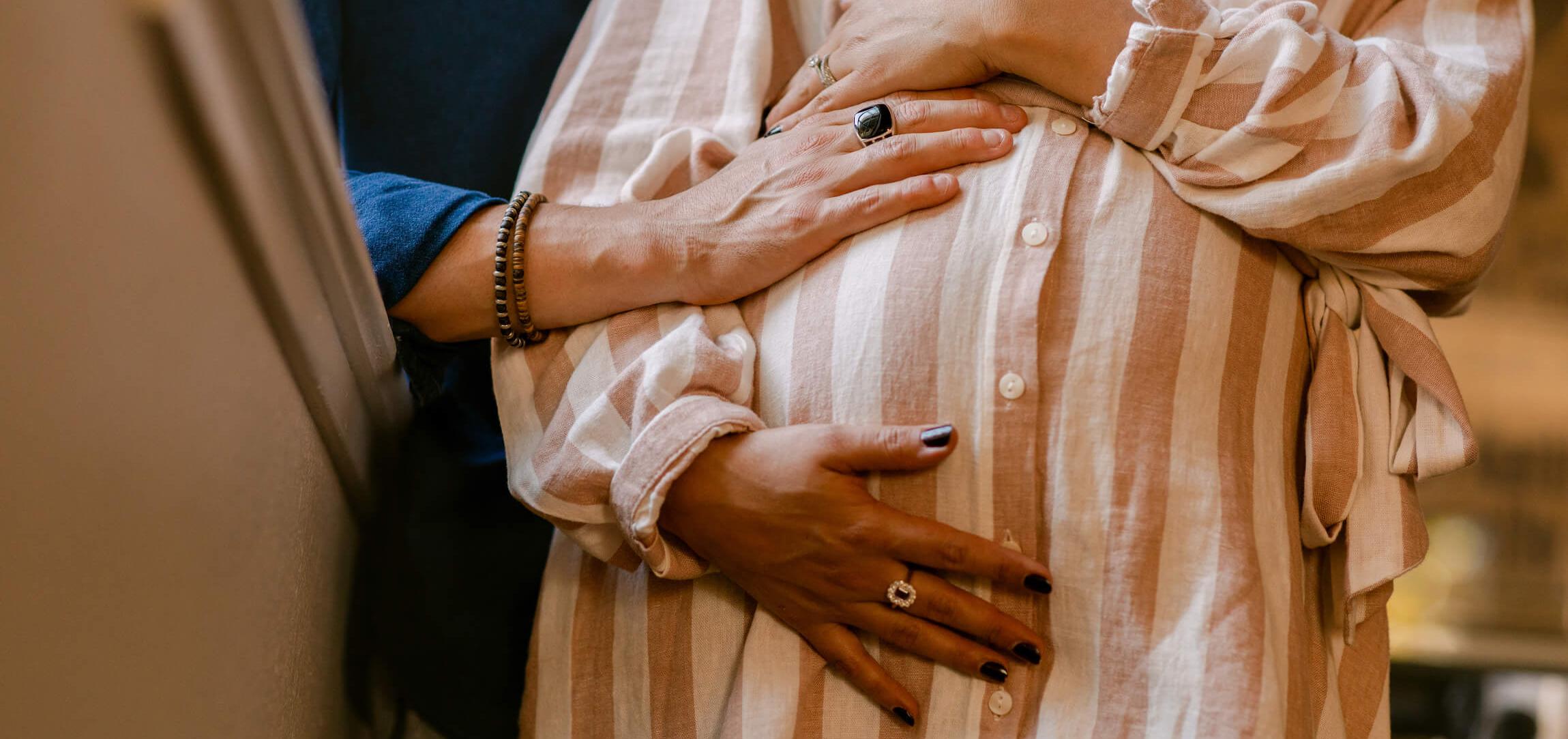 partner and expectant mom with their hands on pregnant belly