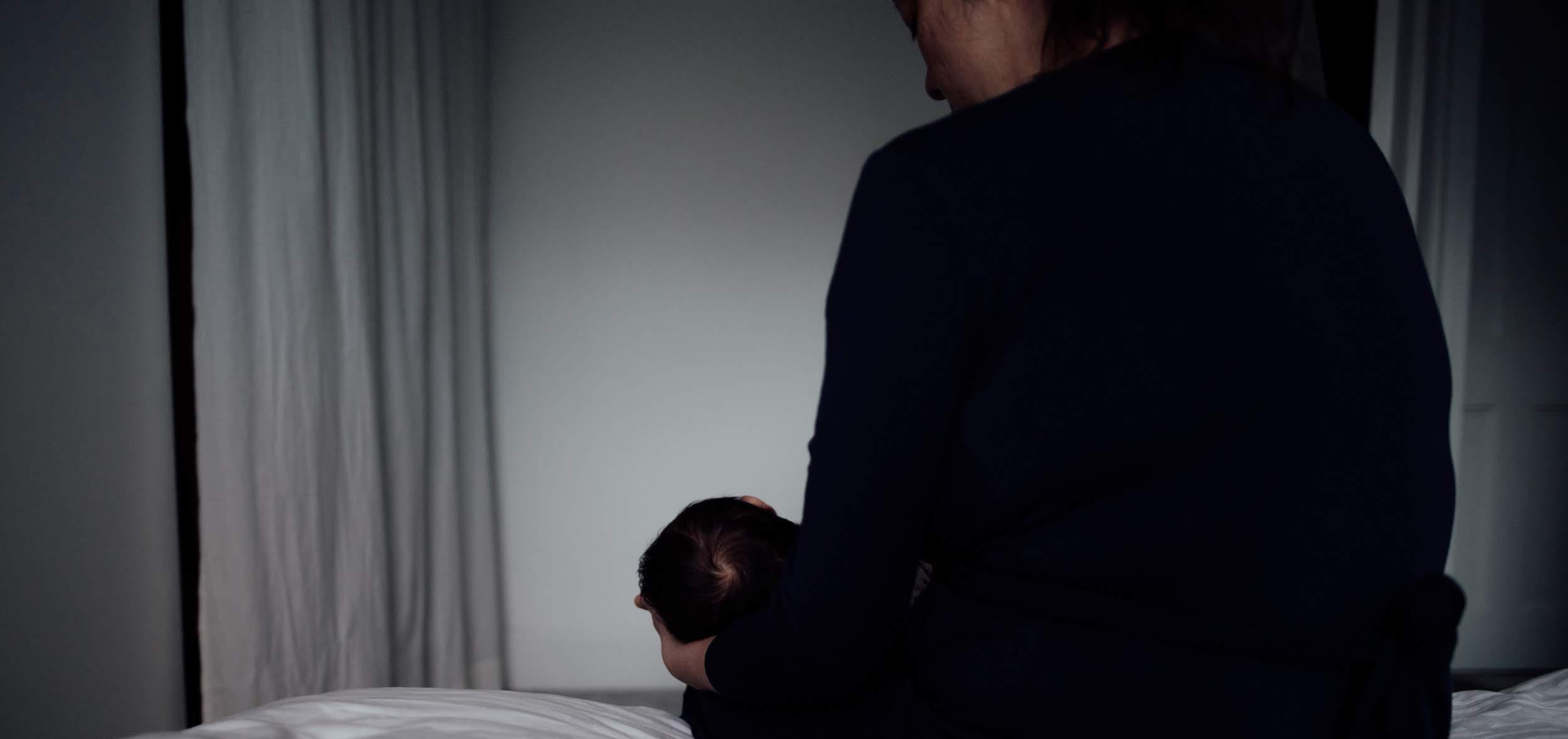 mother sitting on a bed while holding her baby