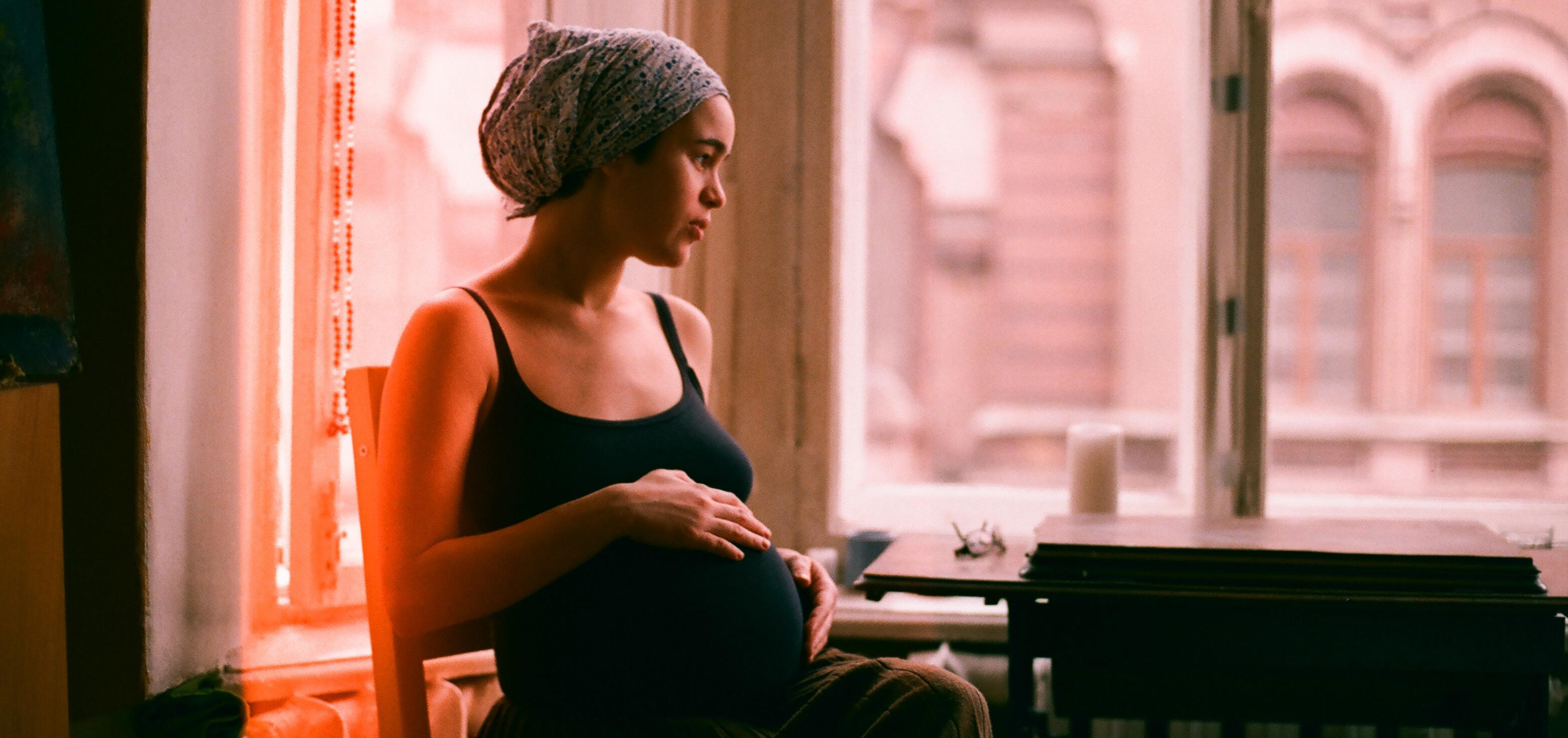 pregnant woman sitting in a chair and staring off into the distance