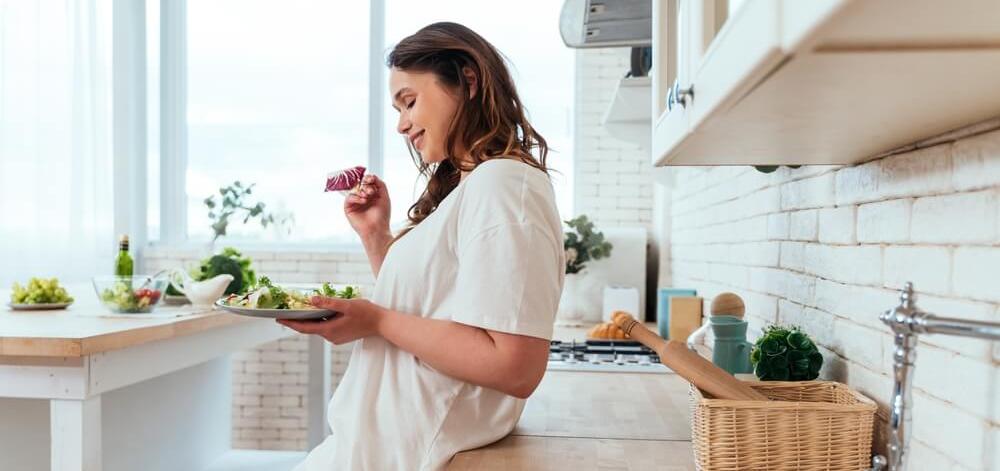 woman eating a light, healthy meal in her kitchen