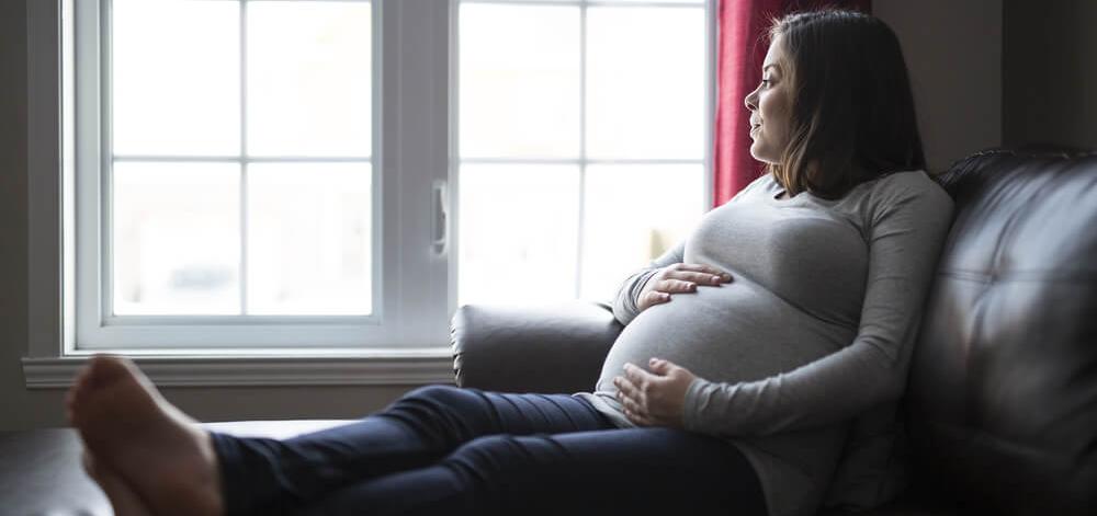 pregnant woman feeling alone, looking out the window