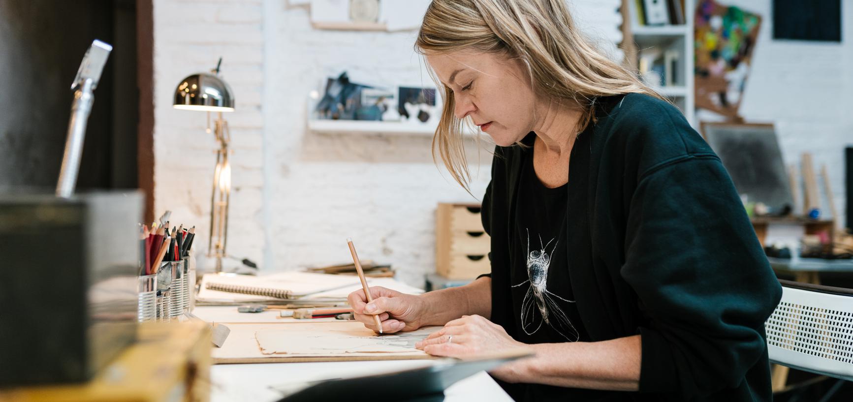 Woman in midlife sketching in a notepad in an art studio