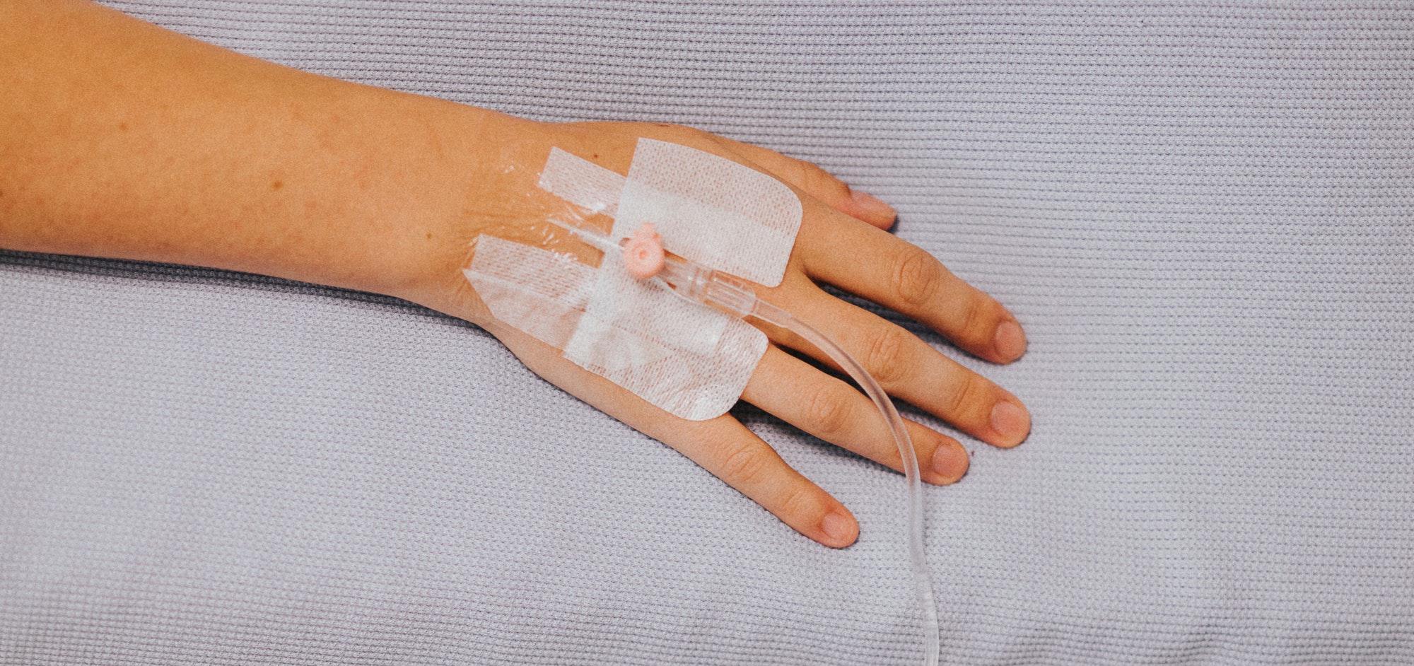 hand with an attached catheter resting on a soft surface