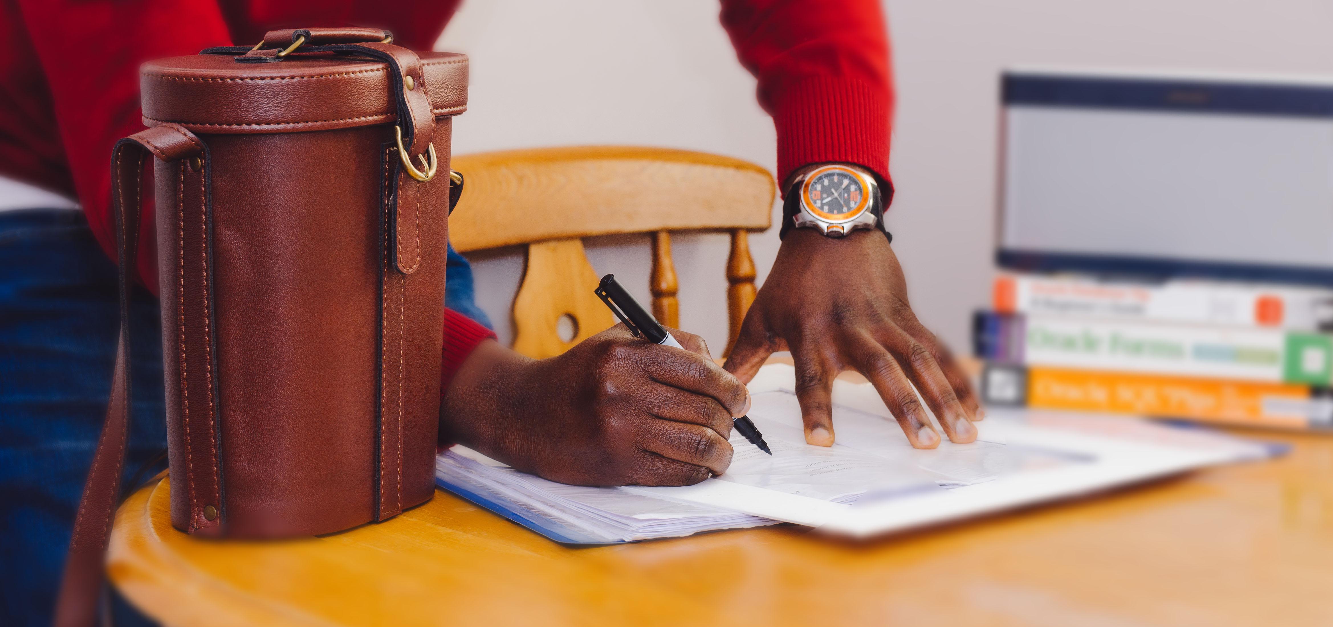 A man writing something down with his work briefcase nearby