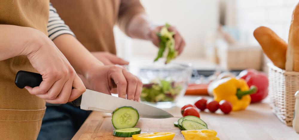 Couple cutting vegetables as part of a plant-based diet