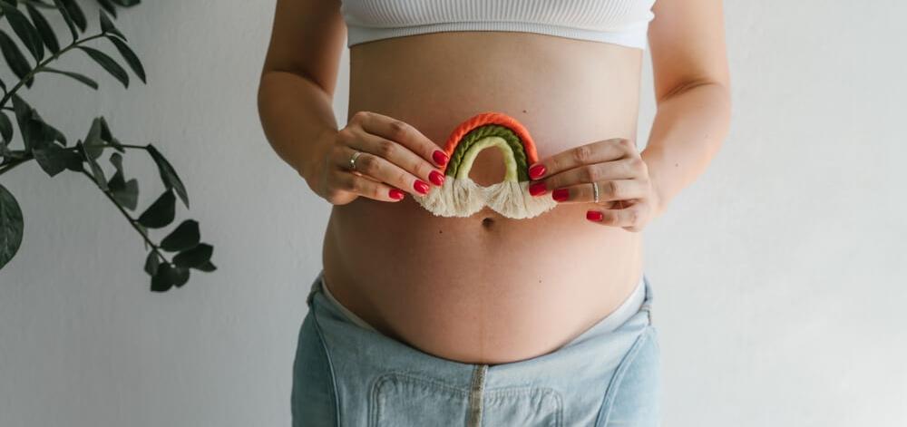 pregnant woman holding rainbow decoration