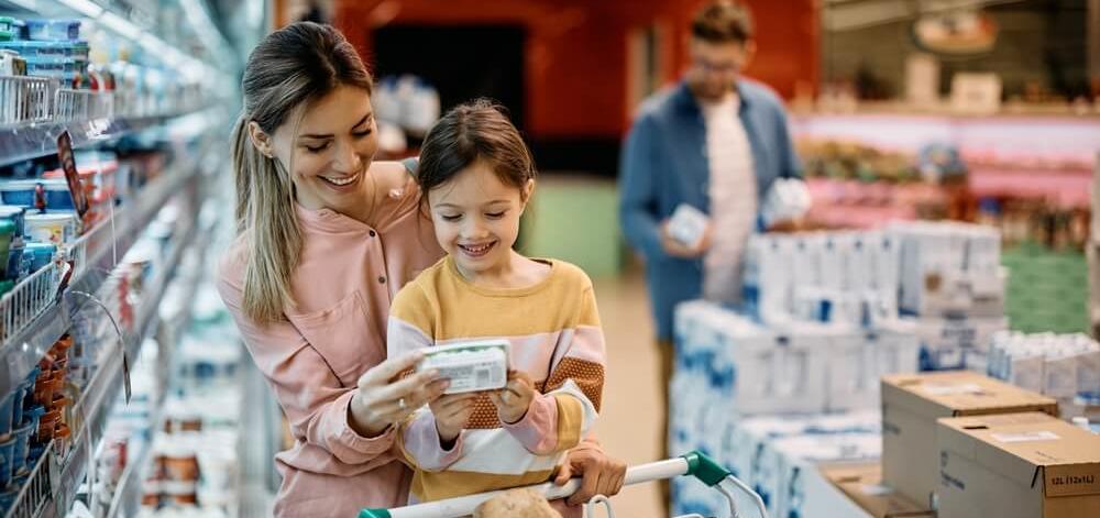 Mother and daughter in a grocery store reading the label on a packaged food item