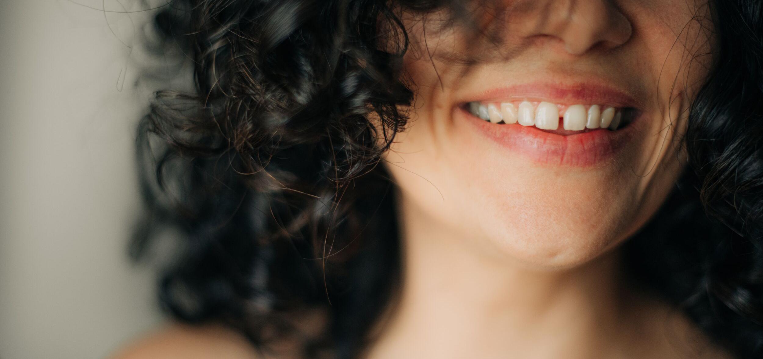 woman with a carefree smile and dark, curly hair