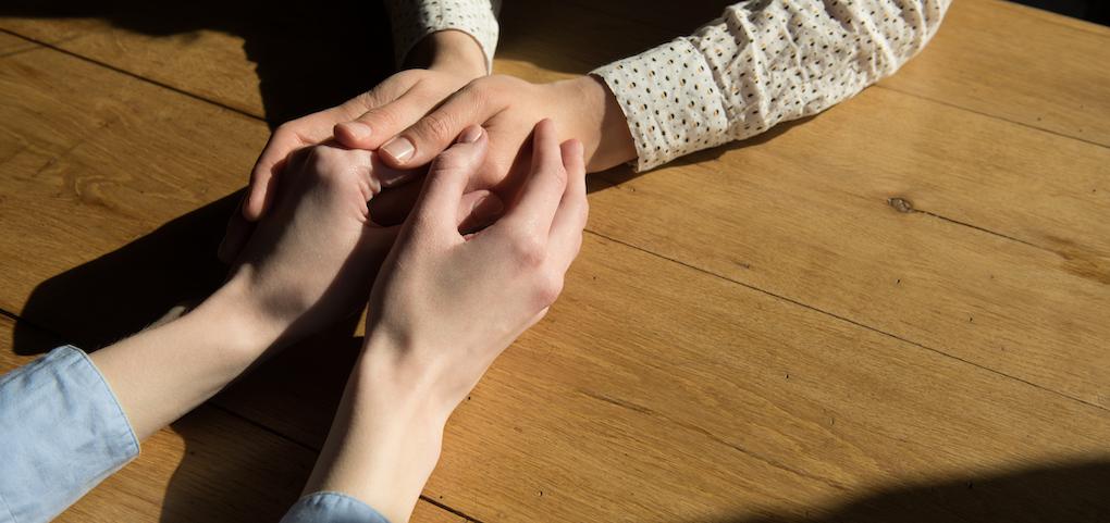 people clasping hands across a table