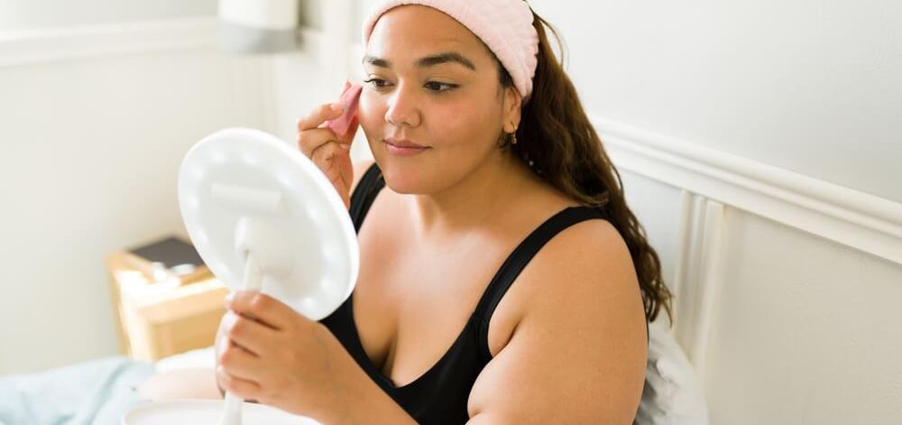 woman in her bedroom looking at her face in a mirror