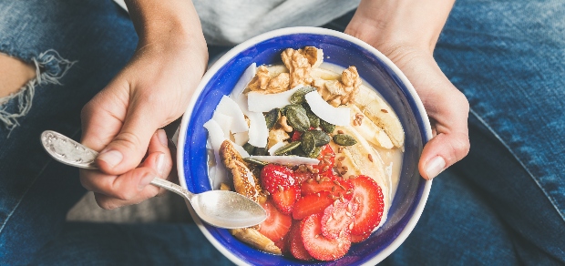 woman holding a bowl of yogurt with fruit